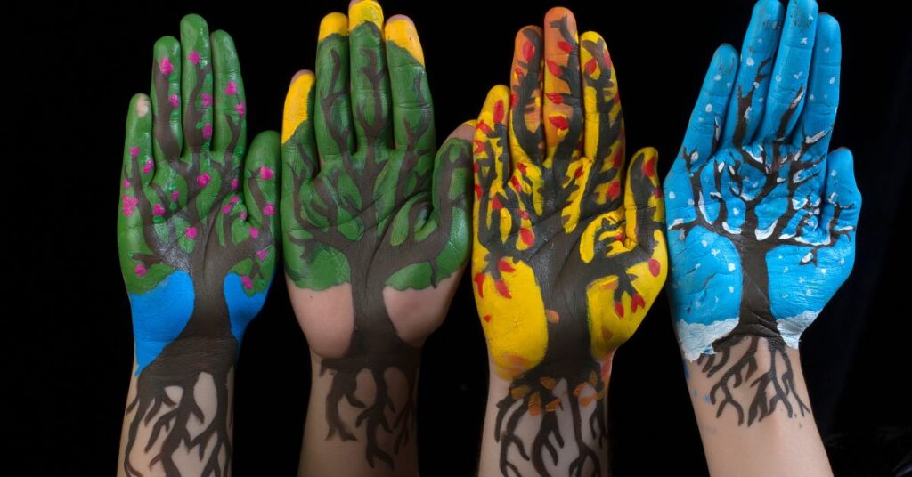 Hands painted with seasonal colors and tree designs for “Finding Steadiness in Seasons of Change”