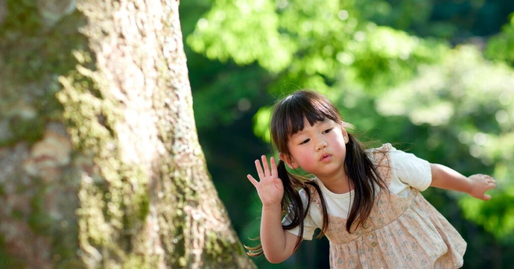 Child leaning toward a tree, listening closely, for “Listening to the Language of Trees”