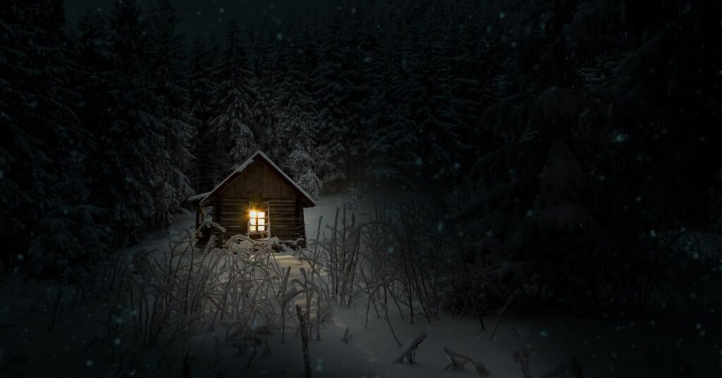 Small cabin glowing with warm light in a snowy forest for “The Longest Night”